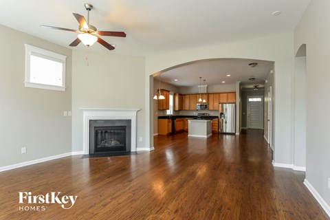 A spacious living room with a fireplace and a ceiling fan.