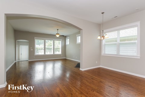 A spacious room with wooden floors and a large arched doorway.