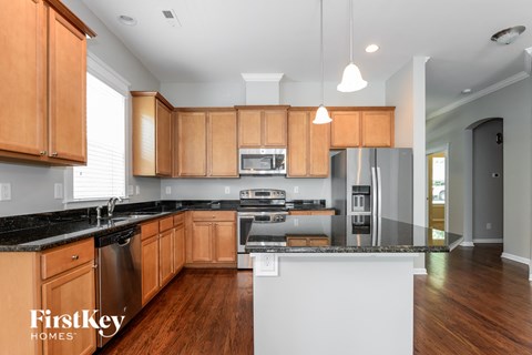 A modern kitchen with wooden cabinets and a black countertop.