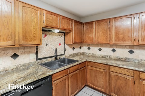 A kitchen with wooden cabinets and a marble countertop.