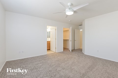 a spacious living room with carpet and a ceiling fan