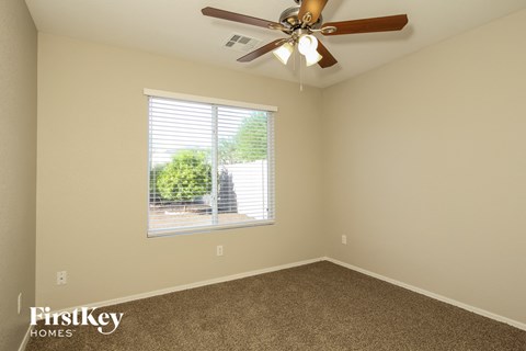 the master bedroom has a ceiling fan and a large window