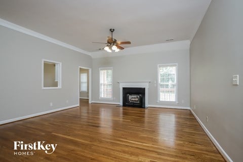 an empty living room with a ceiling fan and a fireplace
