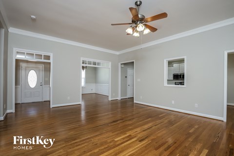 an empty living room with wood floors and a ceiling fan