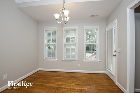 a dining room with a wood floor and three windows