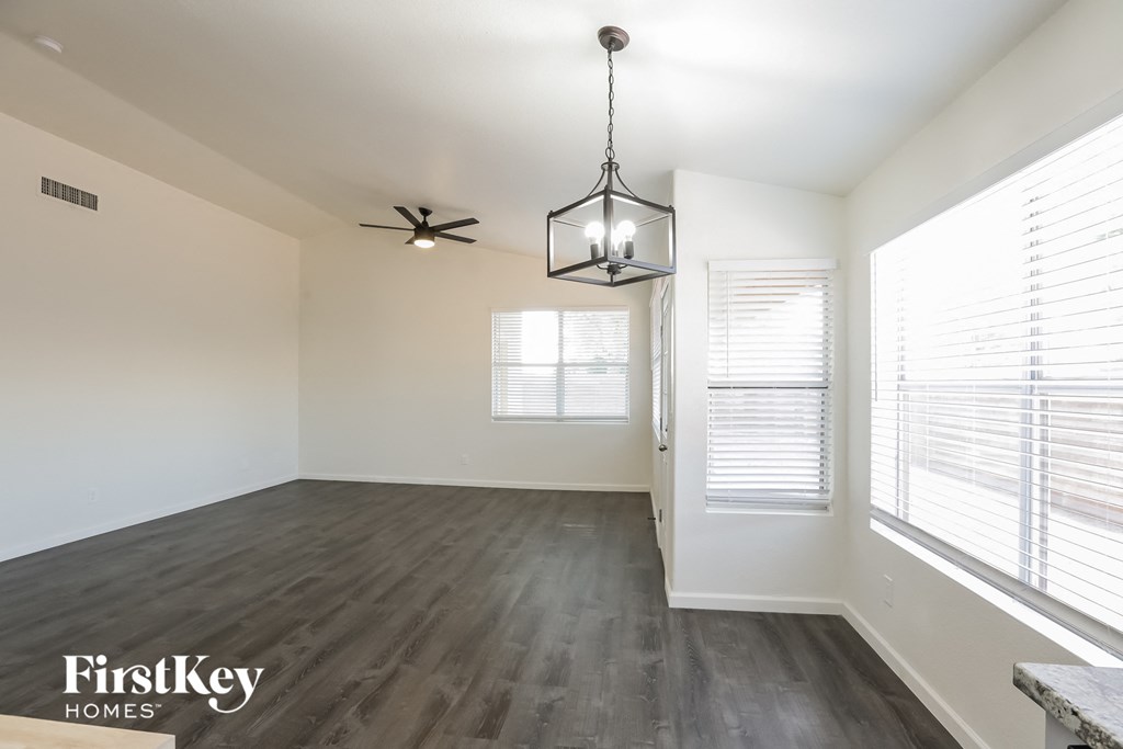 an empty living room with a large window and a ceiling fan