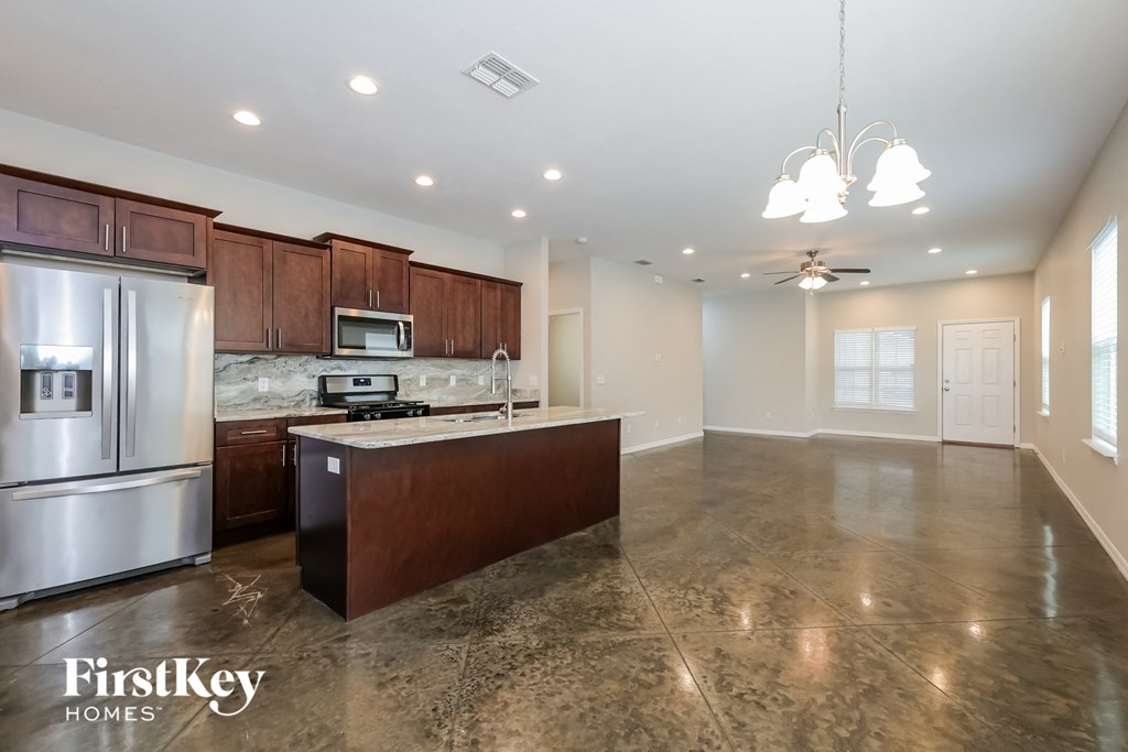 A kitchen with a refrigerator, microwave, and stove top oven.