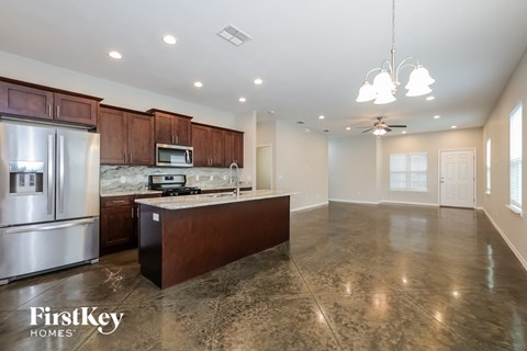 A kitchen with a refrigerator, microwave, and stove top oven.