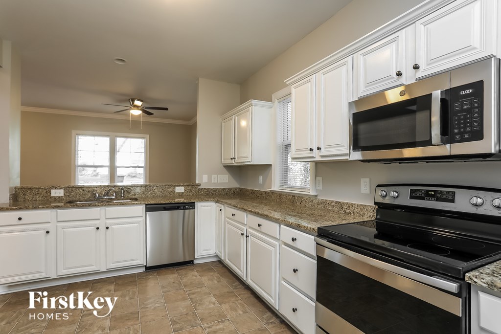 A kitchen with white cabinets and a black stove top oven.