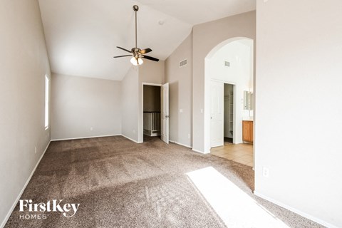a spacious living room with carpet and a ceiling fan
