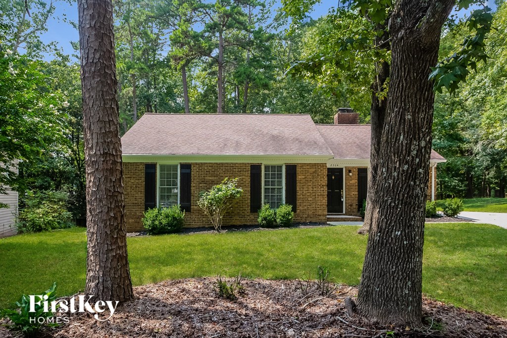 A house with a brown roof and brick walls is surrounded by trees.