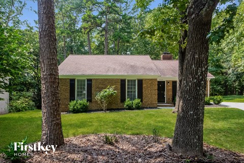 A house with a brown roof and brick walls is surrounded by trees.