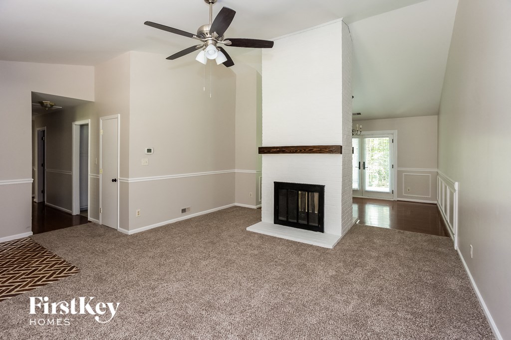 A spacious living room with a fireplace and a ceiling fan.