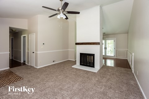 A spacious living room with a fireplace and a ceiling fan.