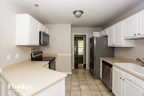 A kitchen with white cabinets and a black fridge.