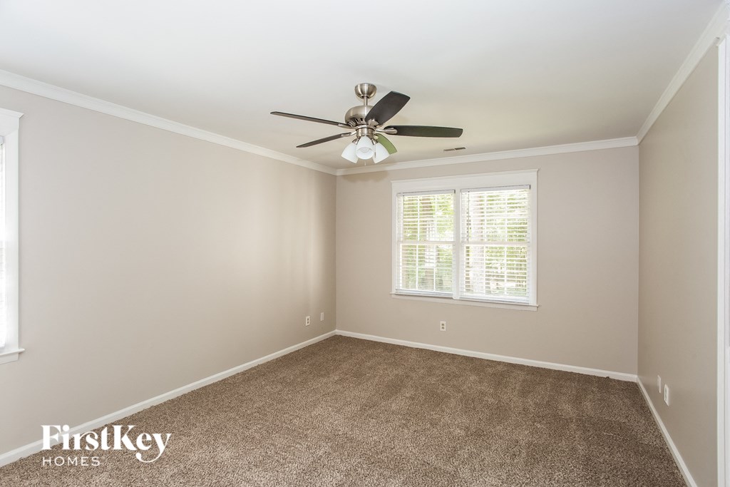 A room with a ceiling fan and a window with blinds.