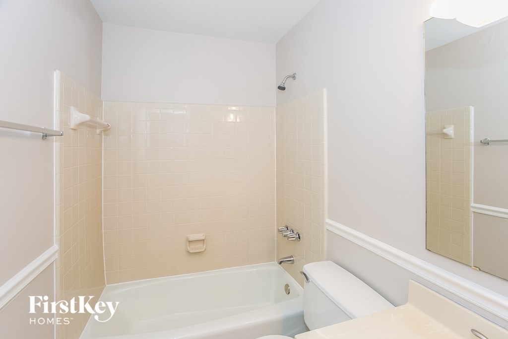 A white bathroom with a tub and a mirror.