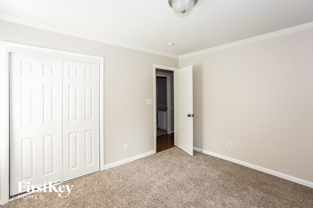 A room with a white door and a brown carpet.