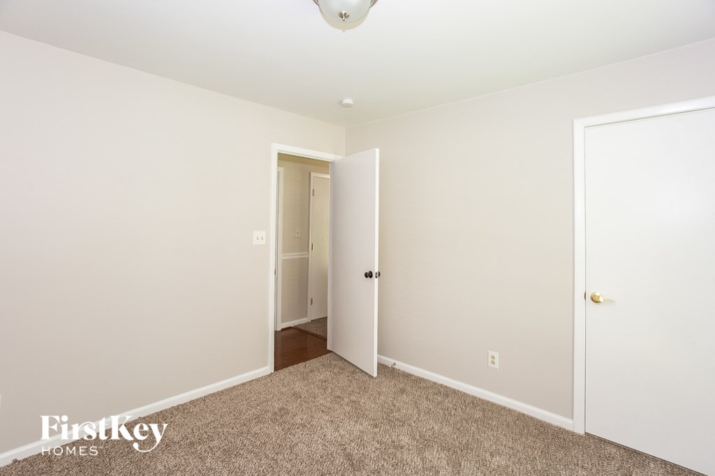 A carpeted room with a doorway leading to another room.