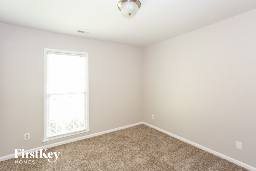 A room with a carpeted floor and a window letting in light.