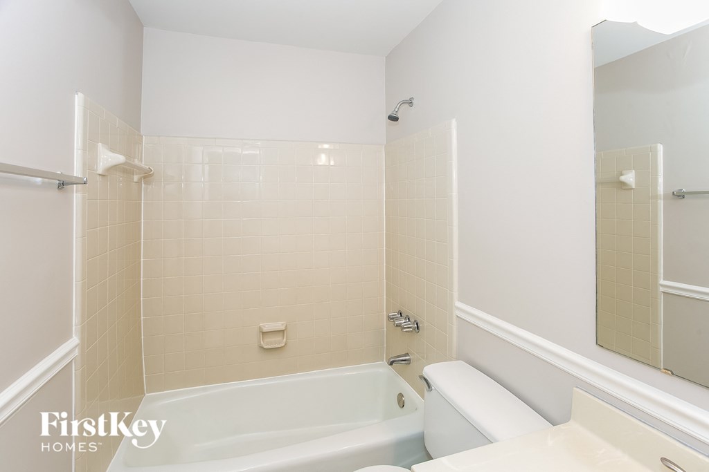 A white bathroom with a tub and a mirror.