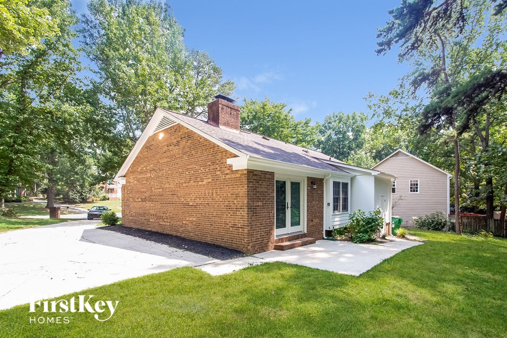 A house with a brick chimney is surrounded by greenery.