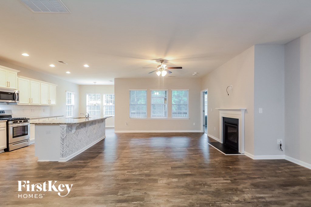 an empty living room with a fireplace and a kitchen