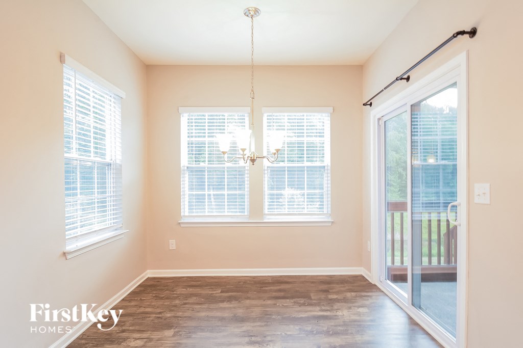 an empty living room with windows and a door to a balcony