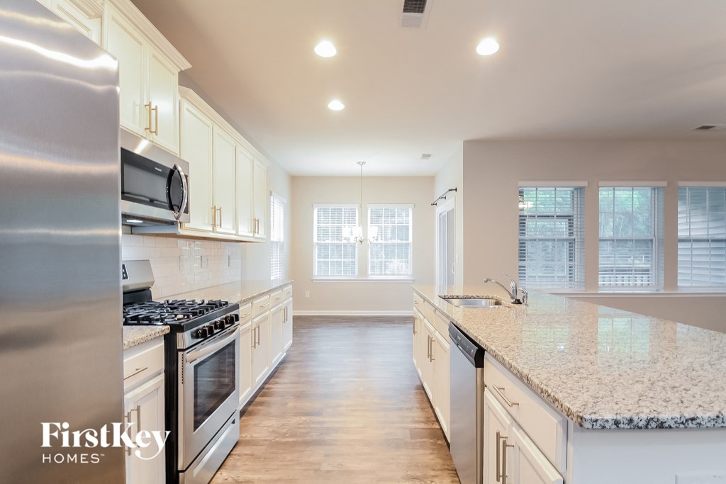 a large kitchen with white cabinets and granite counter tops and stainless steel appliances