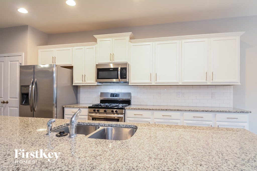 a white kitchen with granite counter tops and stainless steel appliances