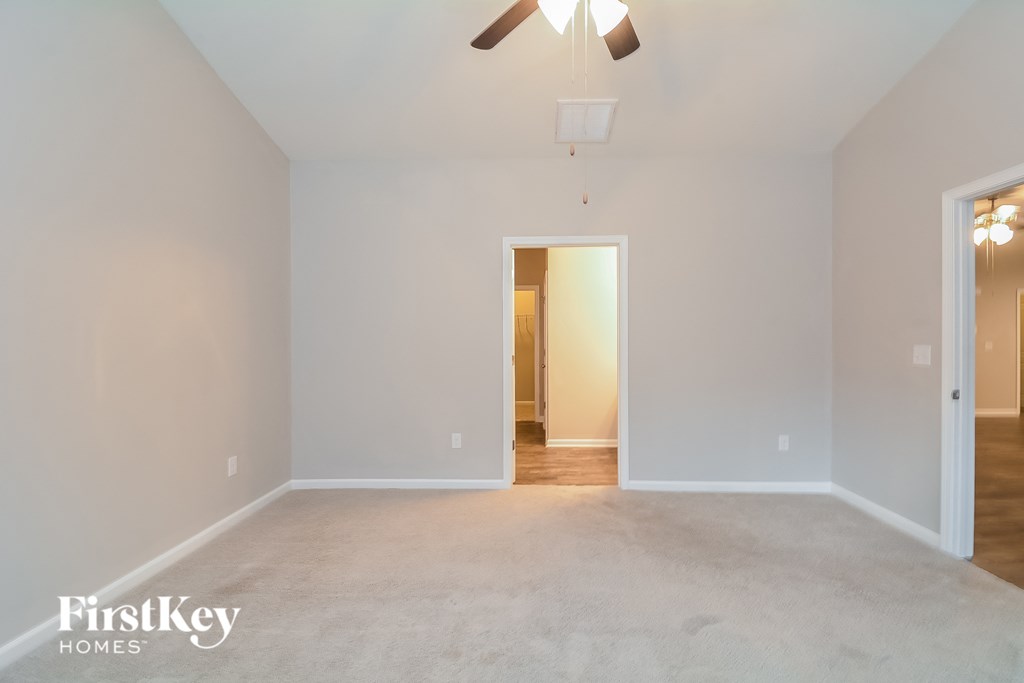 a empty living room with white walls and a ceiling fan