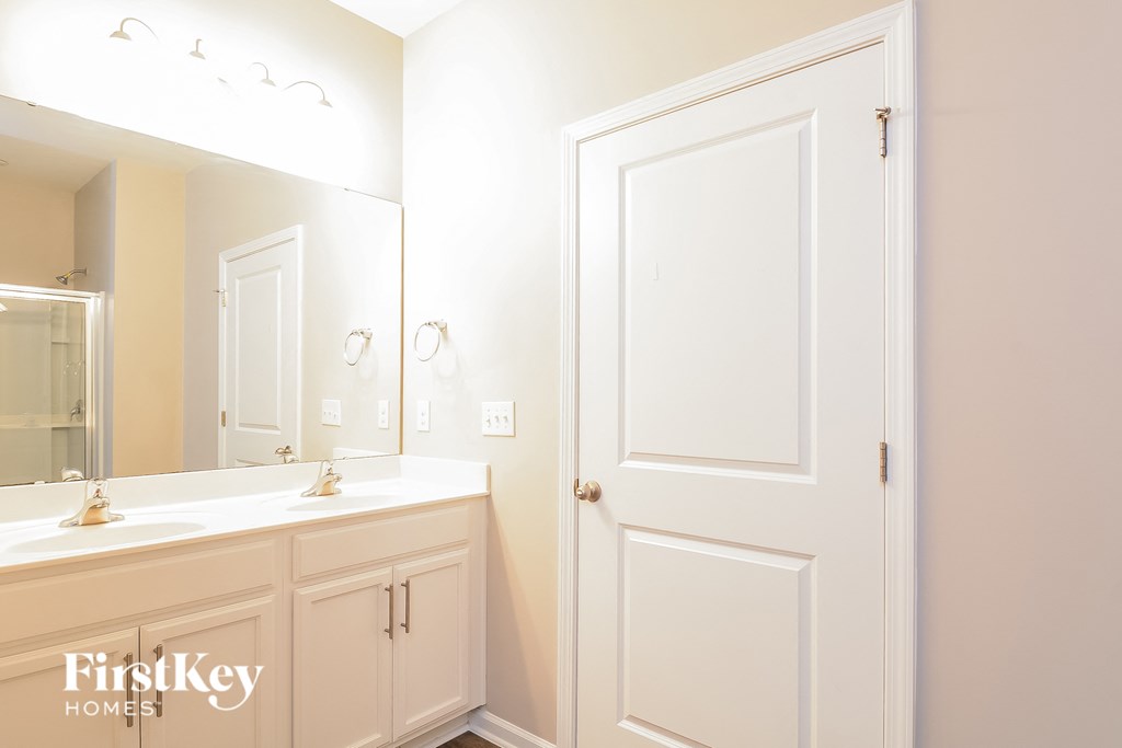 a bathroom with a white door and a sink and a mirror