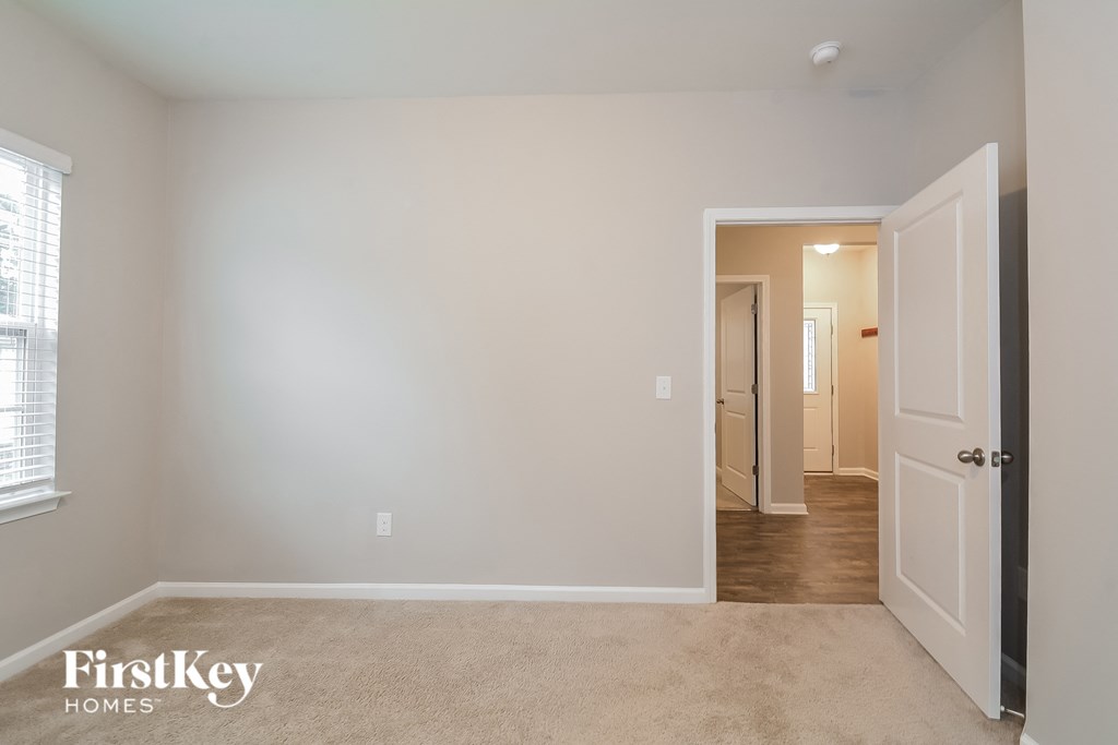 a bedroom with a white wall and a door to a hallway