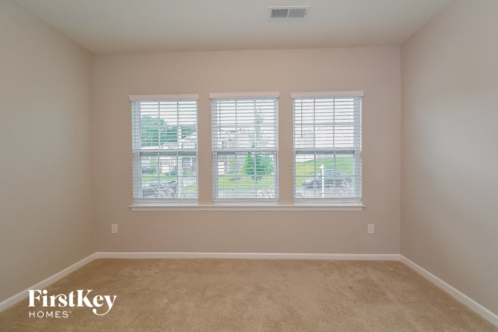a bedroom with three windows and a carpeted floor