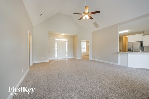 an empty living room with a ceiling fan and white walls
