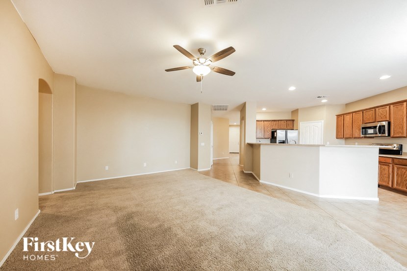 an empty living room and kitchen with a ceiling fan