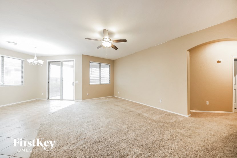 a empty living room with a ceiling fan and a window