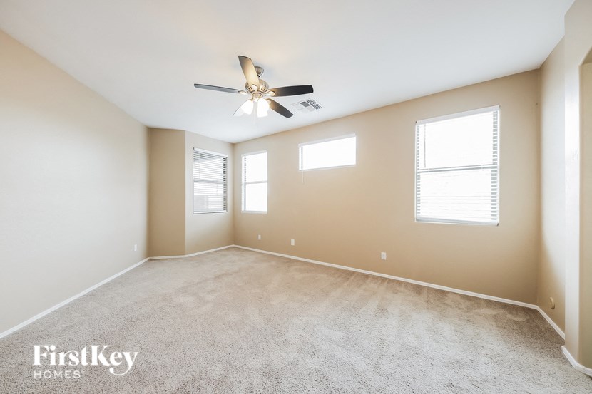 an empty living room with a ceiling fan and two windows