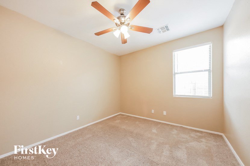 an empty room with a ceiling fan and a window