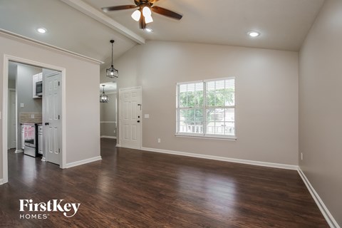 A spacious room with a ceiling fan and wooden flooring.