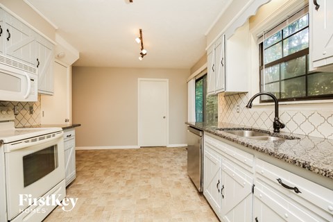 a kitchen with white cabinets and counter tops and a sink