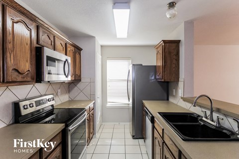 A kitchen with wooden cabinets and a black refrigerator.