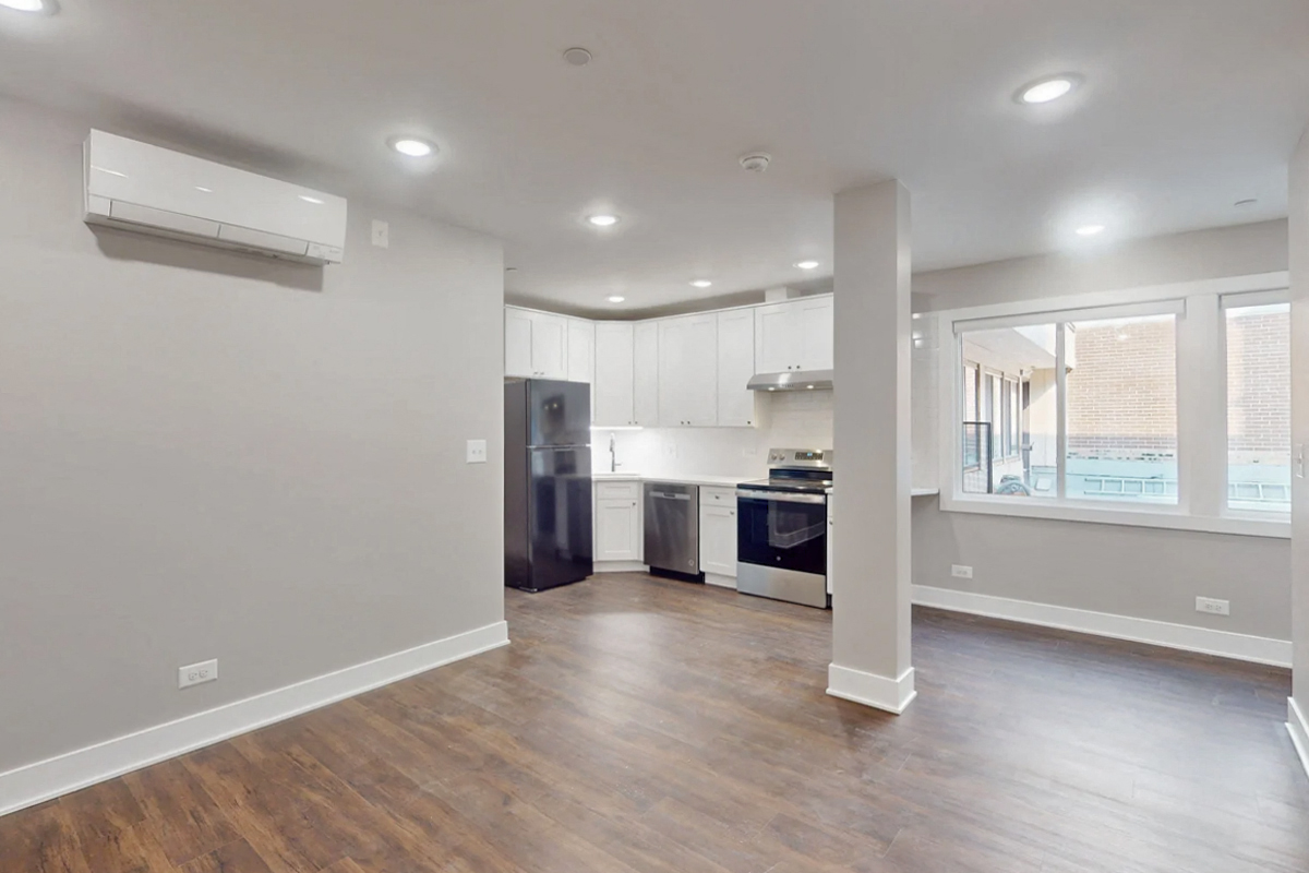 a renovated living room and kitchen with white walls and wood floors
