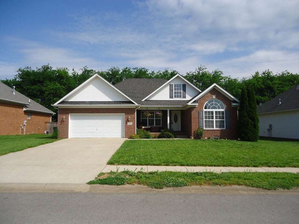 A house with a white garage door is in front of a tree.