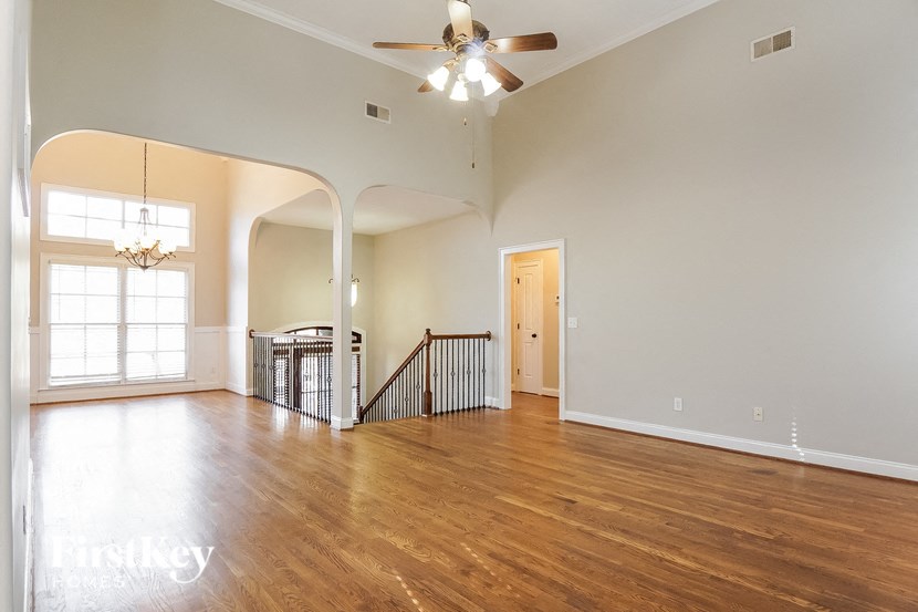A spacious living room with hardwood floors and a ceiling fan.