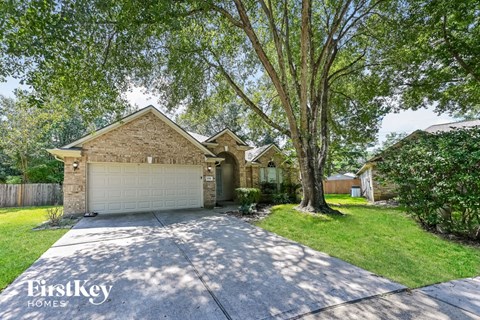 A house with a garage is surrounded by trees and has a driveway leading to it.