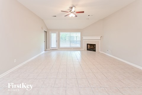 A spacious room with a fireplace and a ceiling fan.