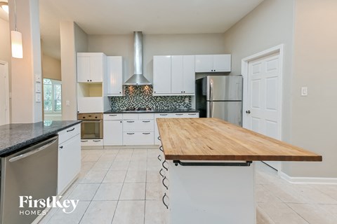 A kitchen with a wooden counter top and white cabinets.