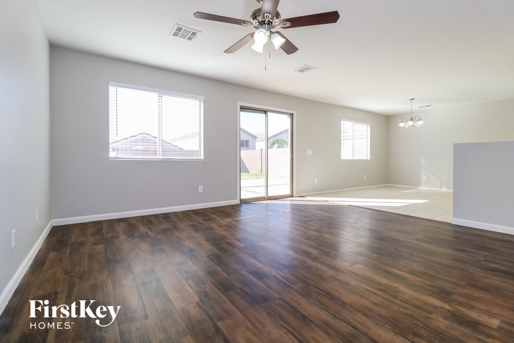 an empty living room with wood floors and a ceiling fan