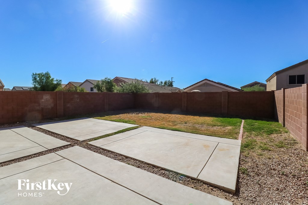 a backyard with a fence and a yard with concrete and grass